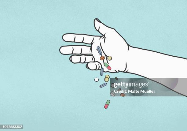 hand dropping pills on blue background - hand holding several pills photos et images de collection
