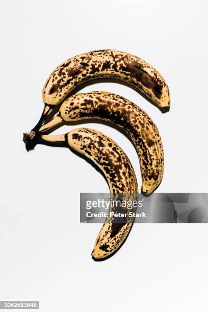rotting, ripe bananas against white background - ripe stock pictures, royalty-free photos & images