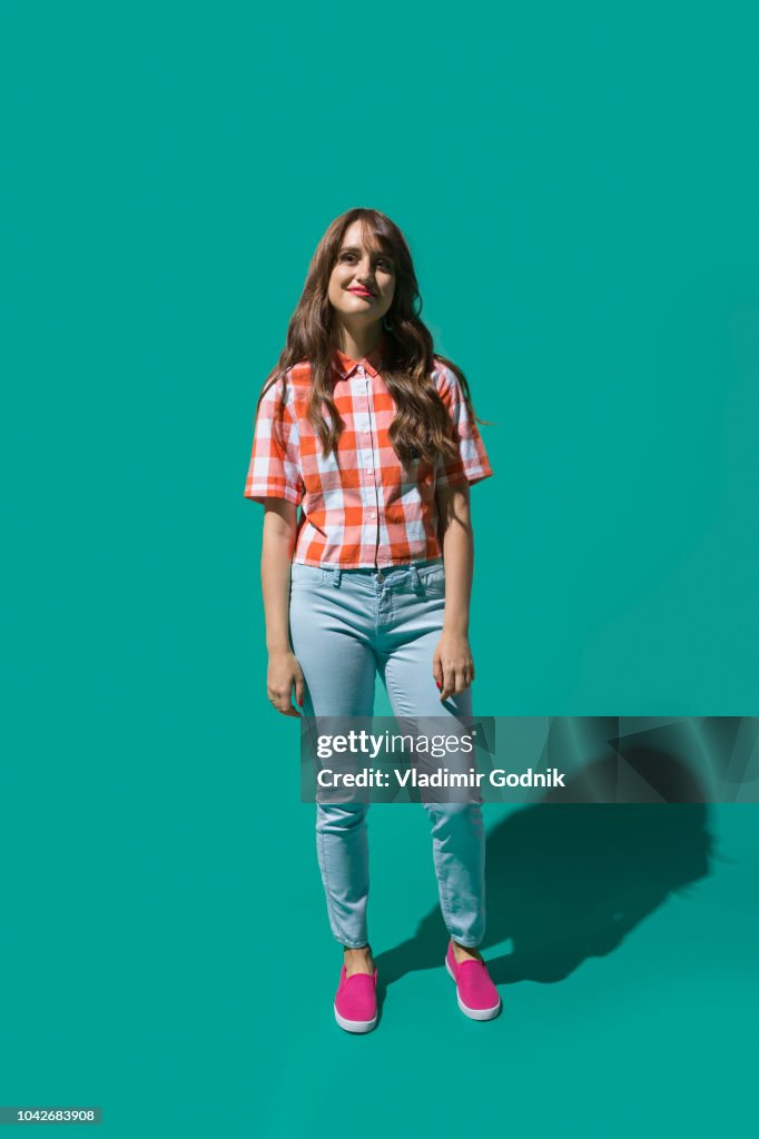 Portrait confident young woman against turquoise background