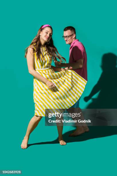 portrait carefree couple dancing against turquoise background - couples studio portrait stock-fotos und bilder