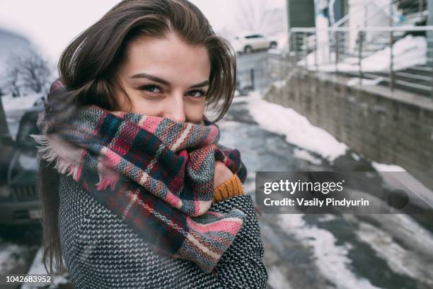 portrait confident young woman in plaid scarf on snowy winter street - vladivostok city stock pictures, royalty-free photos & images