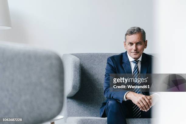 portrait of mature businessman sitting on couch in his office - seat of the european central bank stockfoto's en -beelden