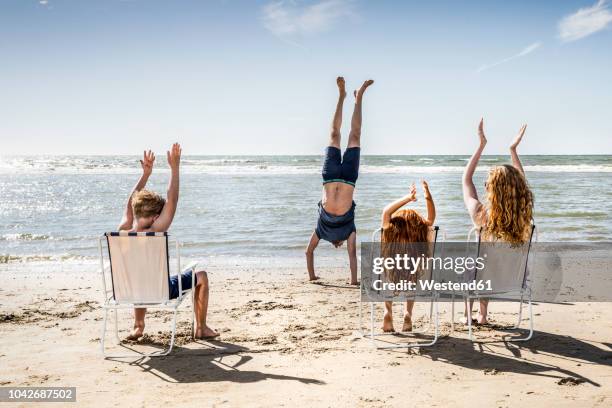 netherlands, zandvoort, family clapping hands for father doing a handstand on the beach - dutch family stockfoto's en -beelden