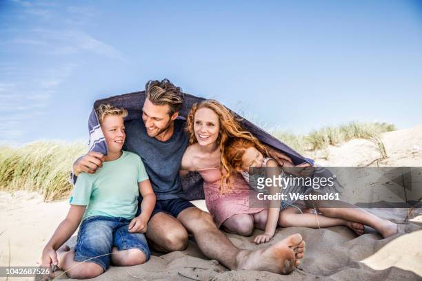 netherlands, zandvoort, happy family under a blanket on the beach - six under ストックフォトと画像