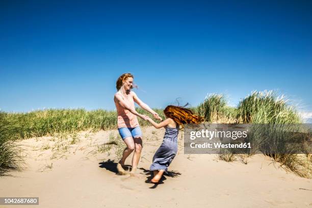 netherlands, zandvoort, happy mother and daughter dancing in beach dunes - dancing for ned stock pictures, royalty-free photos & images