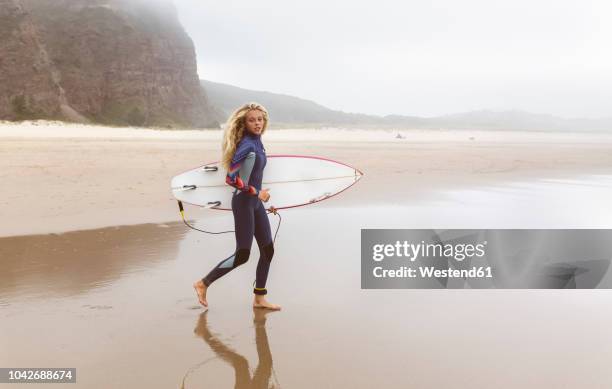 spain, aviles, young surfer walking towards the water - young teen girl beach ストックフォトと画像