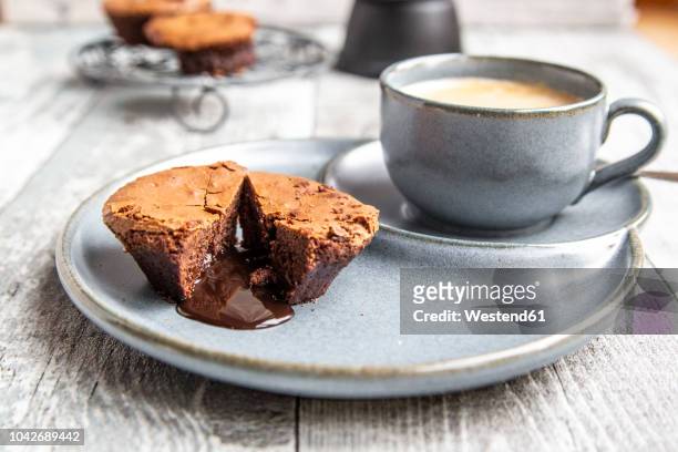 chocolate muffin with liquid chocolate on plate with coffee cup - coffee with chocolate stock pictures, royalty-free photos & images