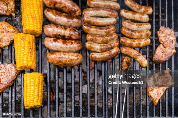 different meat, maize and fried sausages on barbecue grill - charcoal food stock pictures, royalty-free photos & images