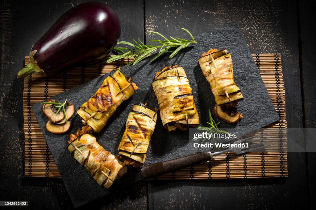 Grilled aubergine slices stuffed with mincemeat, champignons and goat cheese on slate