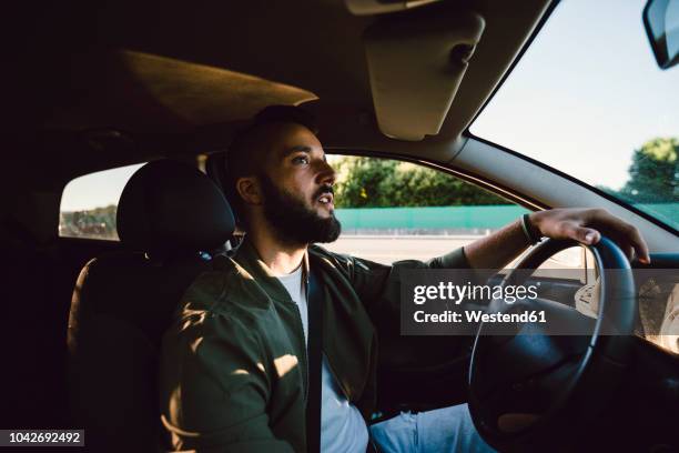 bearded young man looking at rear-view mirror while driving car - rear view mirror 個照片及圖片檔