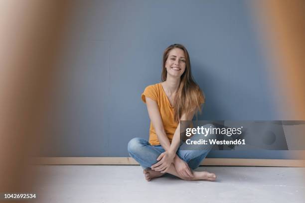 happy woman sitting on ground, barefoot with legs crossed, laughing - pernas cruzadas imagens e fotografias de stock