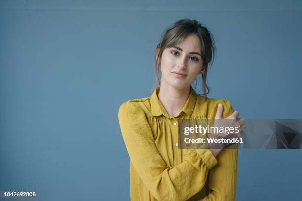 portrait of a young woman wearing a yellow blouse - portrait blue background stock-fotos und bilder