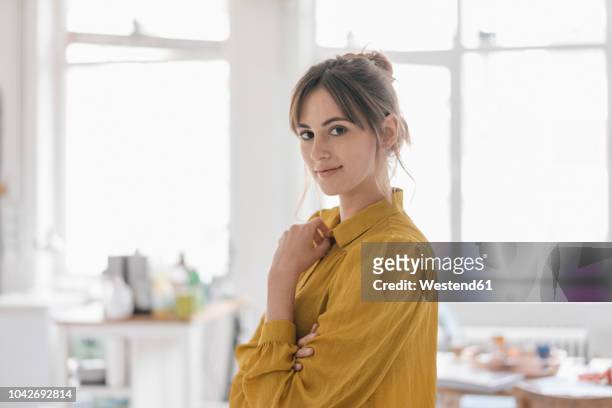 portrait of a young woman at home, wearing a yellow blouse - blouse fotografías e imágenes de stock