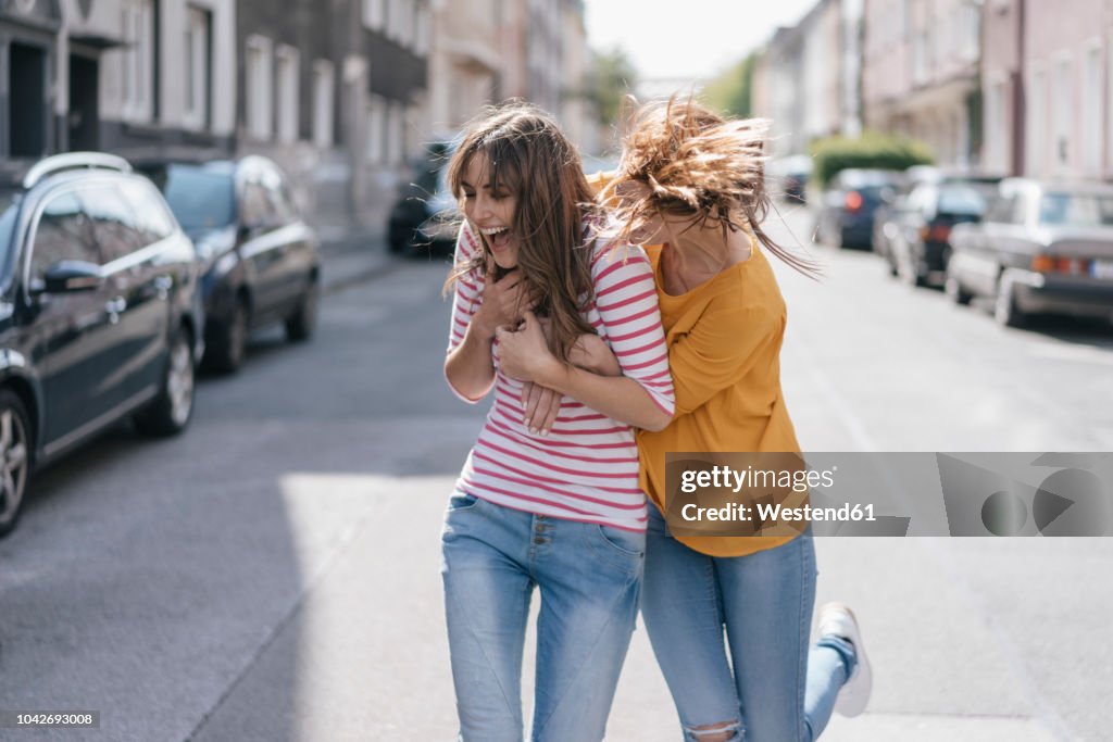 Two girlfriends having fun in the city, running