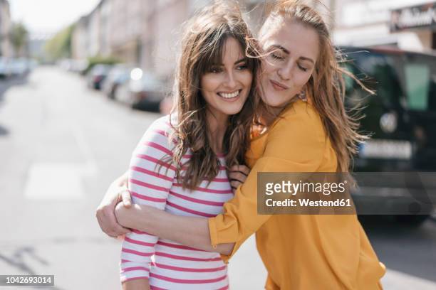 two girlfriends embracing in the city - positive emotionen stock-fotos und bilder