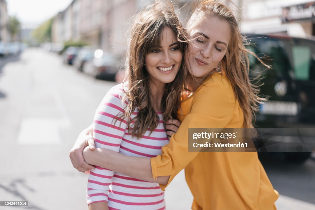 Two girlfriends embracing in the city