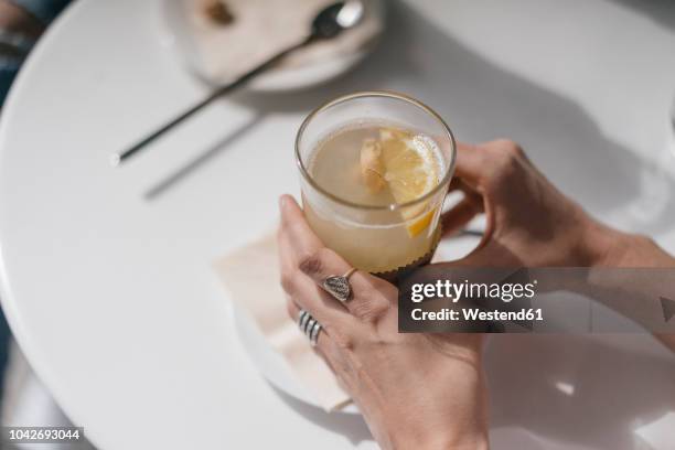 woman holding glass of ginger lemon tea - ginger root stock pictures, royalty-free photos & images