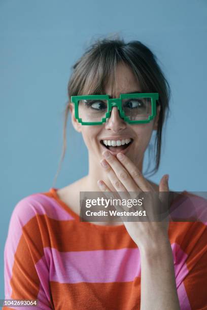 young woman wearing pixel glasses, looking cross-eyed - nerd woman stock-fotos und bilder