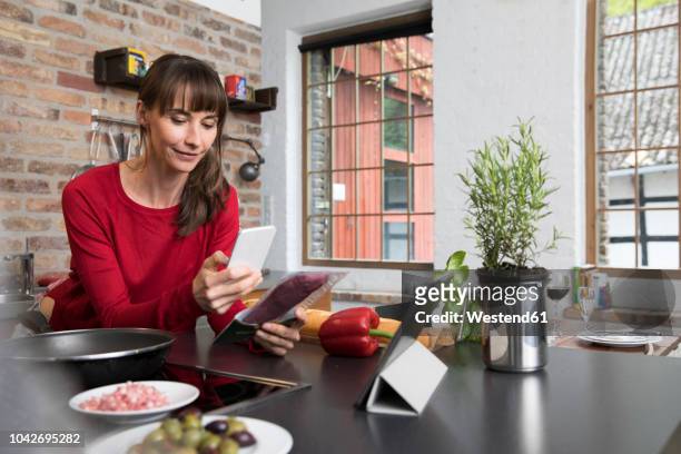 woman in kitchen scanning products with her smartphone - woman cooking phone stock-fotos und bilder