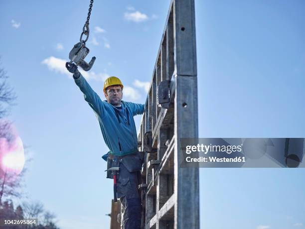 construction worker reaching for hook of crane - hook equipment stock pictures, royalty-free photos & images