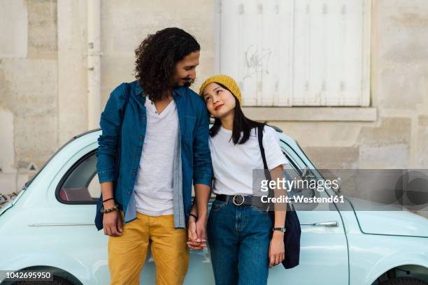 young couple in love standing at small car - french building stock-fotos und bilder