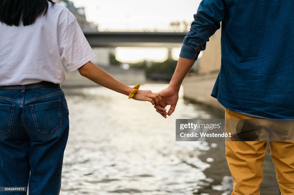 France, Paris, couple holding hands at river Seine