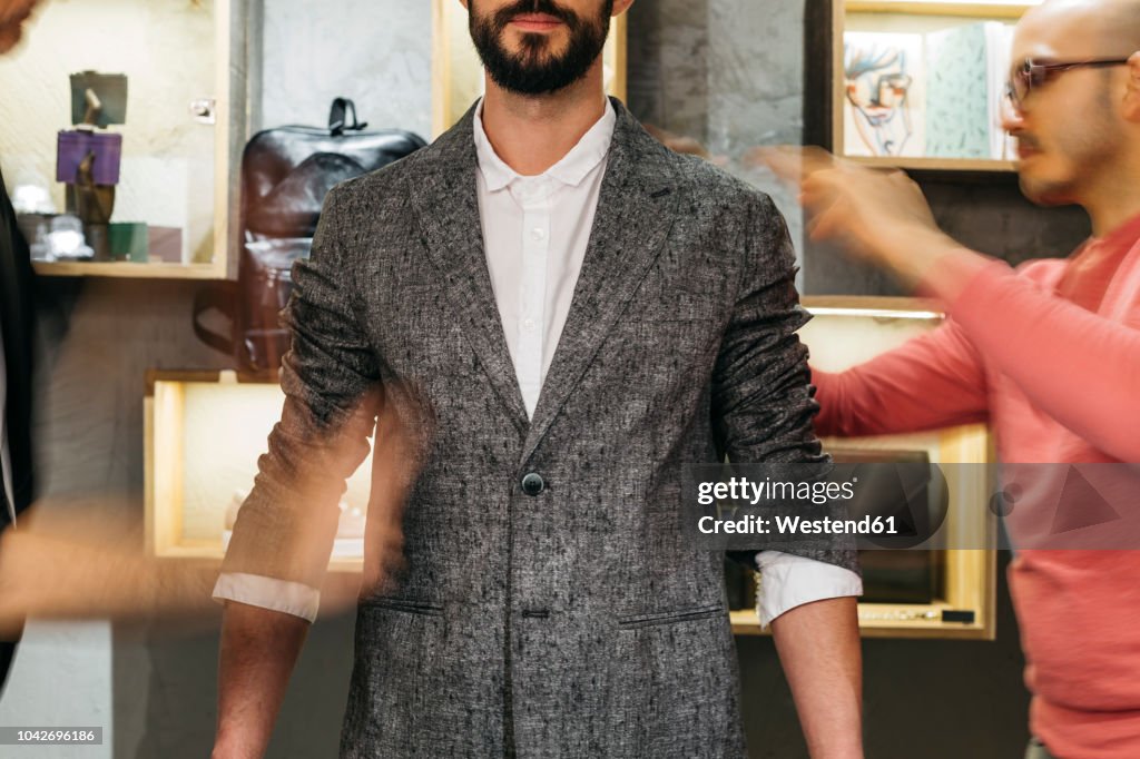 Two men working on new stylish look for handsome man in showroom