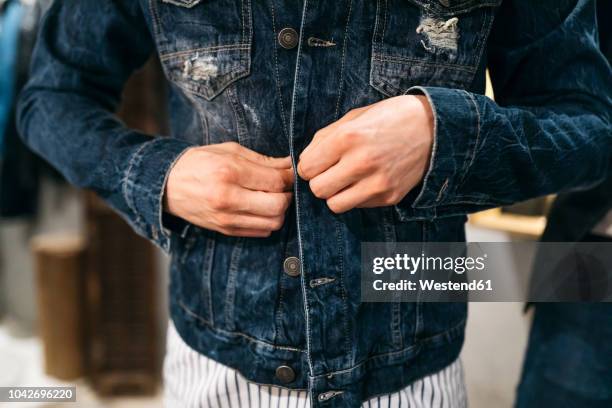 man trying on new denim jacket - denim jacket 個照片及圖片檔