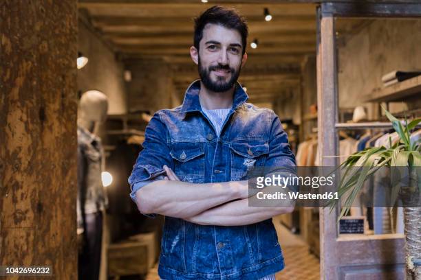 portrait of smiling man wearing denim jacket in menswear shop - boutique entrance stock pictures, royalty-free photos & images