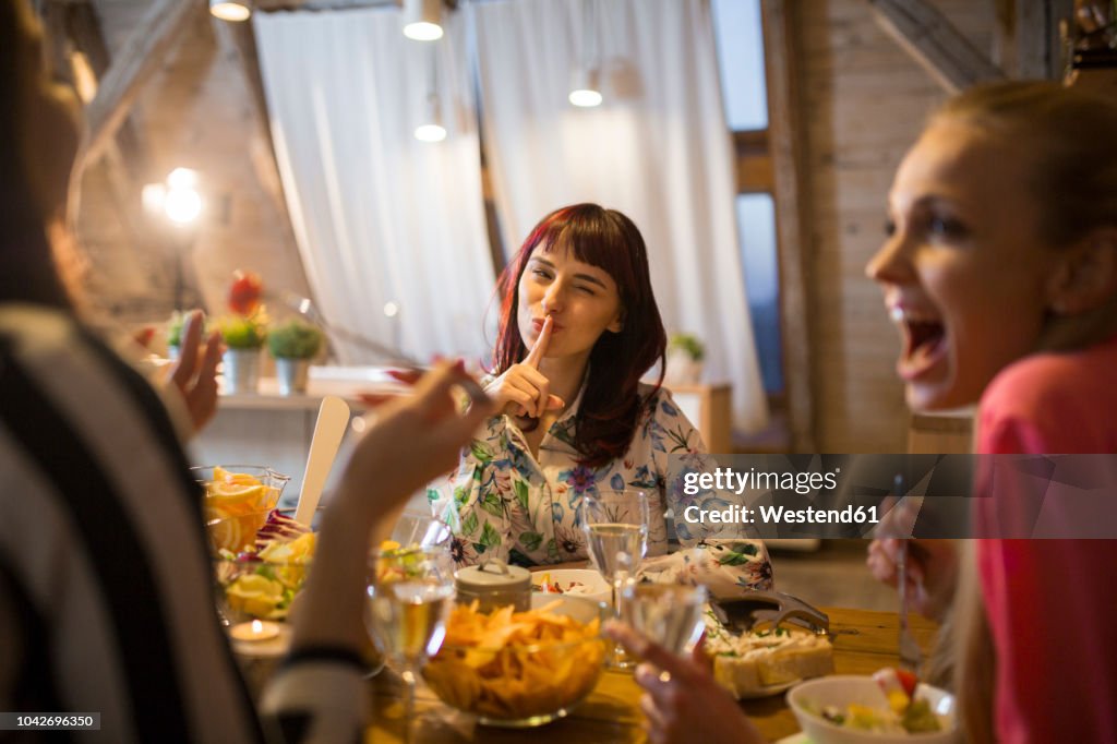 Happy female friends having dinner at home together