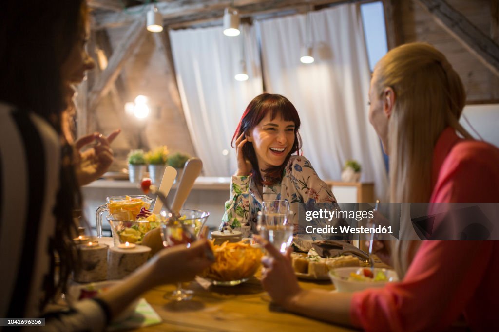 Happy female friends having dinner at home together
