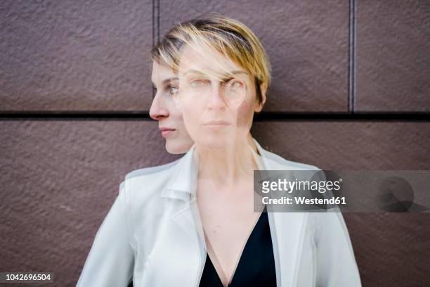 blond businesswoman leaning against wall, dopple exposure - woman short hair serious stock pictures, royalty-free photos & images
