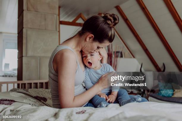 mother cuddling with her baby son - mutter baby stock-fotos und bilder