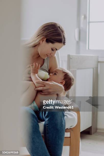 mother feeding her baby son - baby bottle stock pictures, royalty-free photos & images