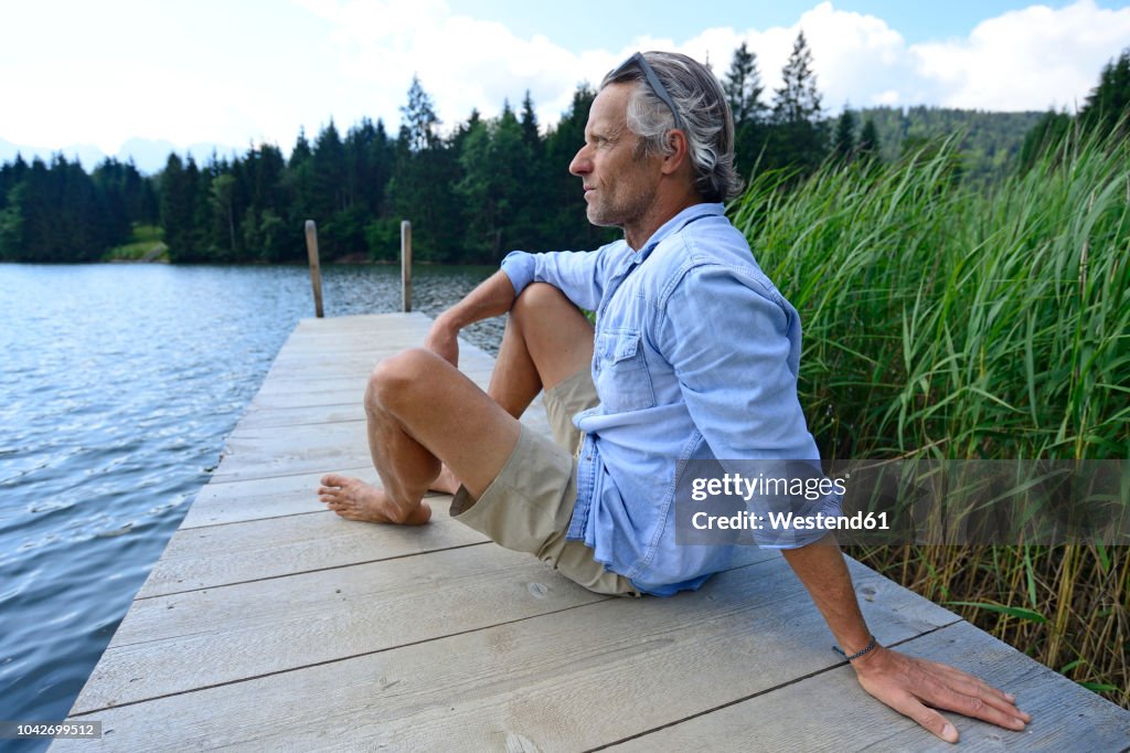 Germany, Mittenwald, mature man relaxing on jetty at lake