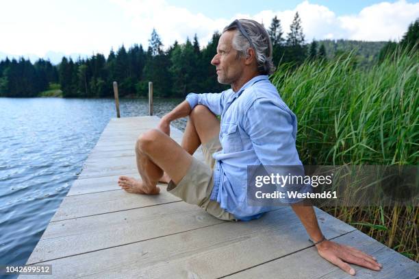 germany, mittenwald, mature man relaxing on jetty at lake - gray shorts stock pictures, royalty-free photos & images