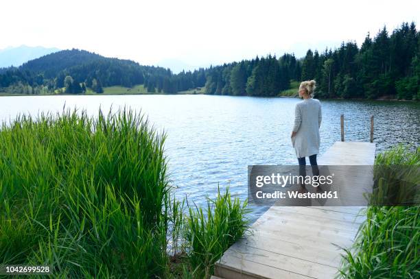 germany, mittenwald, woman standing on jetty at lake looking at distance - woman full body behind stock-fotos und bilder