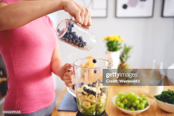 young woman preparing smoothie in the kitchen, partial view - kiwi berries stock-fotos und bilder