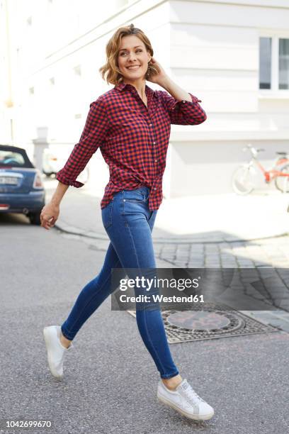 portrait of happy woman crossing the street - camicetta a quadri foto e immagini stock