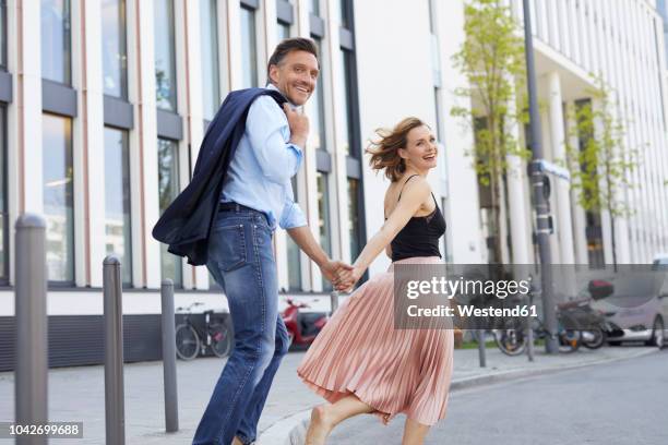 happy couple crossing the street hand in hand - woman hand crossed stockfoto's en -beelden