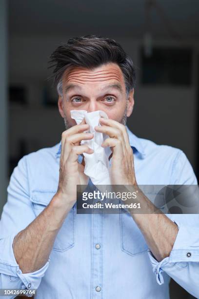 portrait of man blowing nose - snuit stockfoto's en -beelden