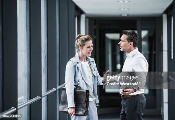 businesswoman and businessman arguing in office passageway - workplace conflict stockfoto's en -beelden