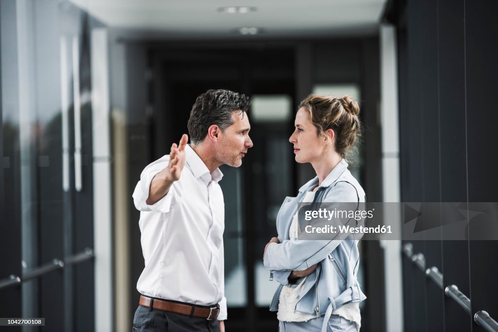 Businesswoman and businessman arguing in office passageway