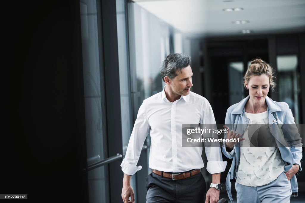 Businesswoman and businessman talking in office passageway