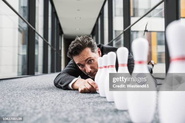 diligent manager lying on the floor in office passageway adjusting pins - bowling pins stock-fotos und bilder
