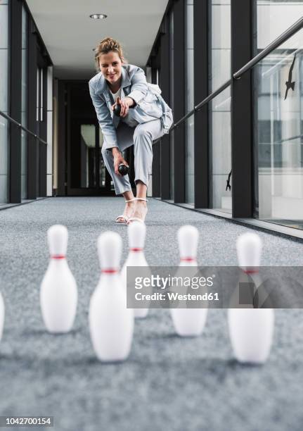 smiling businessman bowling in office passageway - weird hobbies stock pictures, royalty-free photos & images