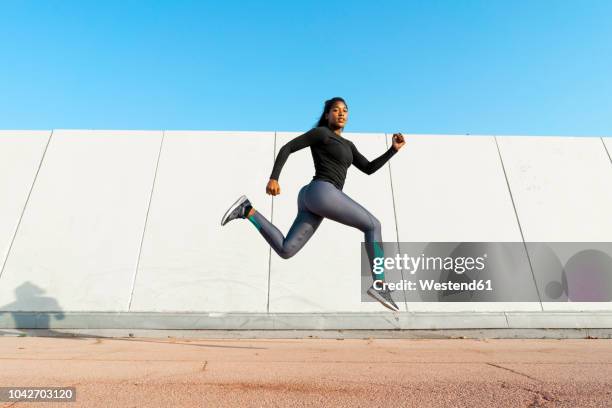 young woman jumgping during workout - ropa de deporte fotografías e imágenes de stock