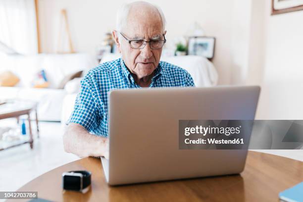 porrtait of senior man at home learning to use laptop - senior men computer stock pictures, royalty-free photos & images