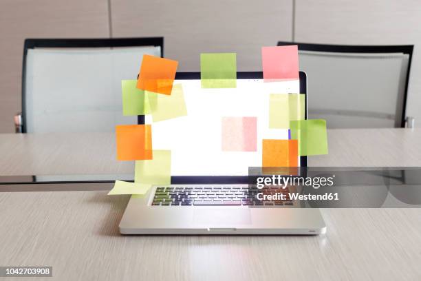opened laptop with plenty of coloured adhesive labels on conference table - tarea doméstica fotografías e imágenes de stock