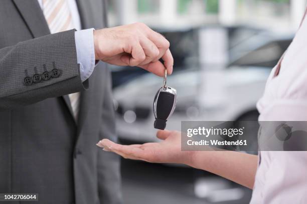 at the car dealer, salesman handing over car key to client - car dealership test drive stock pictures, royalty-free photos & images